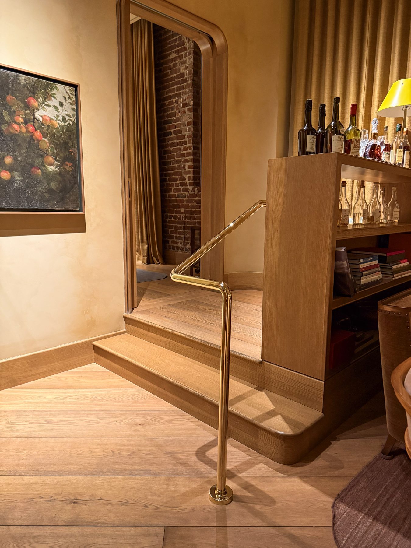 Polished brass handrail alongside a wood stair